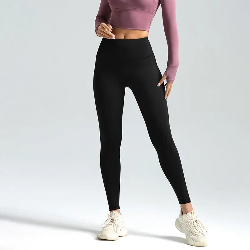 A woman wearing high-waist seamless booty-lifting yoga leggings in black color, paired with a sports bra and white sneakers.
