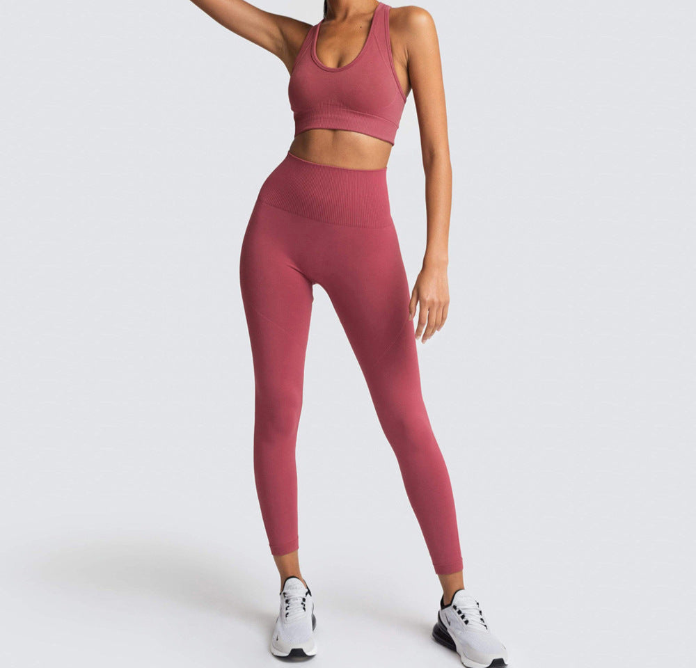 A woman wearing a matching set of green seamless fitness clothing, including high-waisted leggings and a sports bra, standing against a white background.