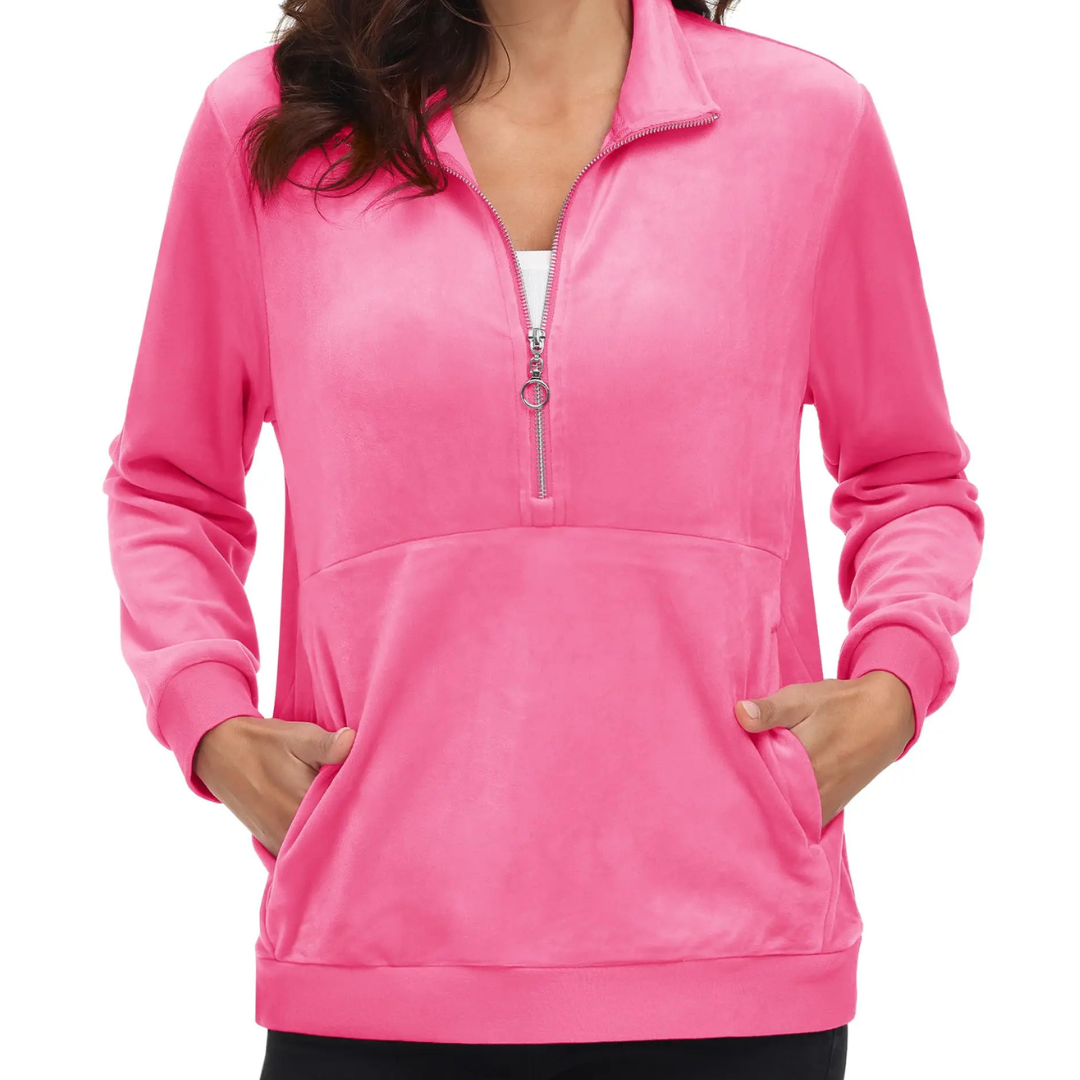 A woman wearing a rose red half zip fleece pullover hoodie with a hood, standing with hands in pockets.