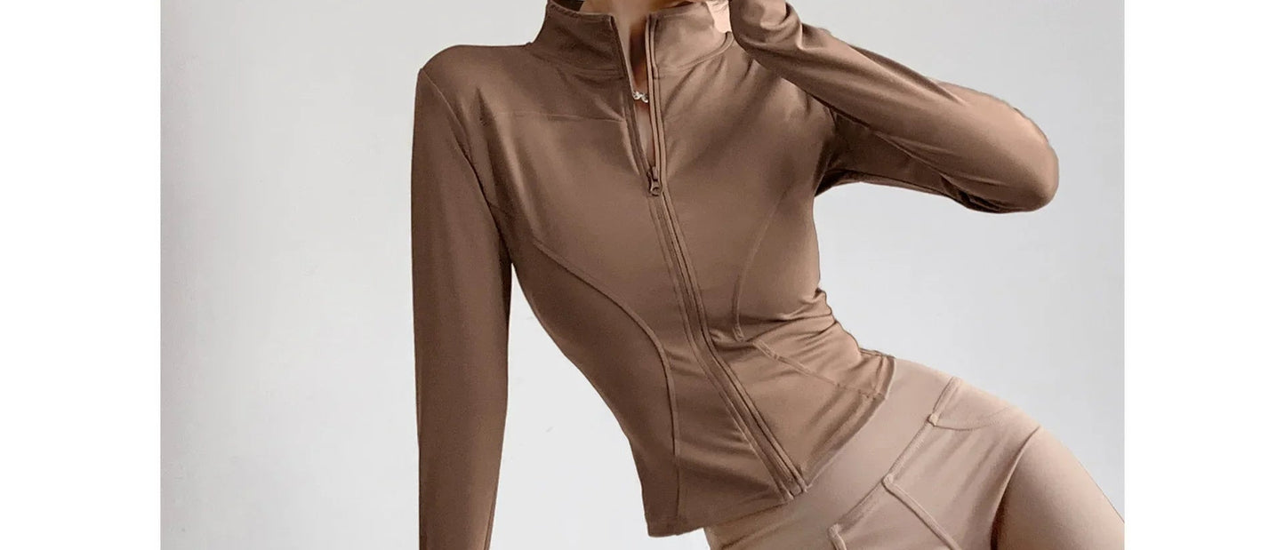 Beige long-sleeve athletic top with a high collar on a light gray background