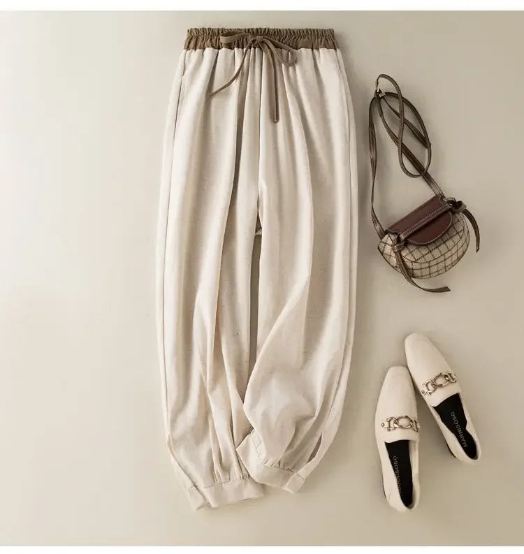 Beige pants with a small handbag and white shoes on a light background