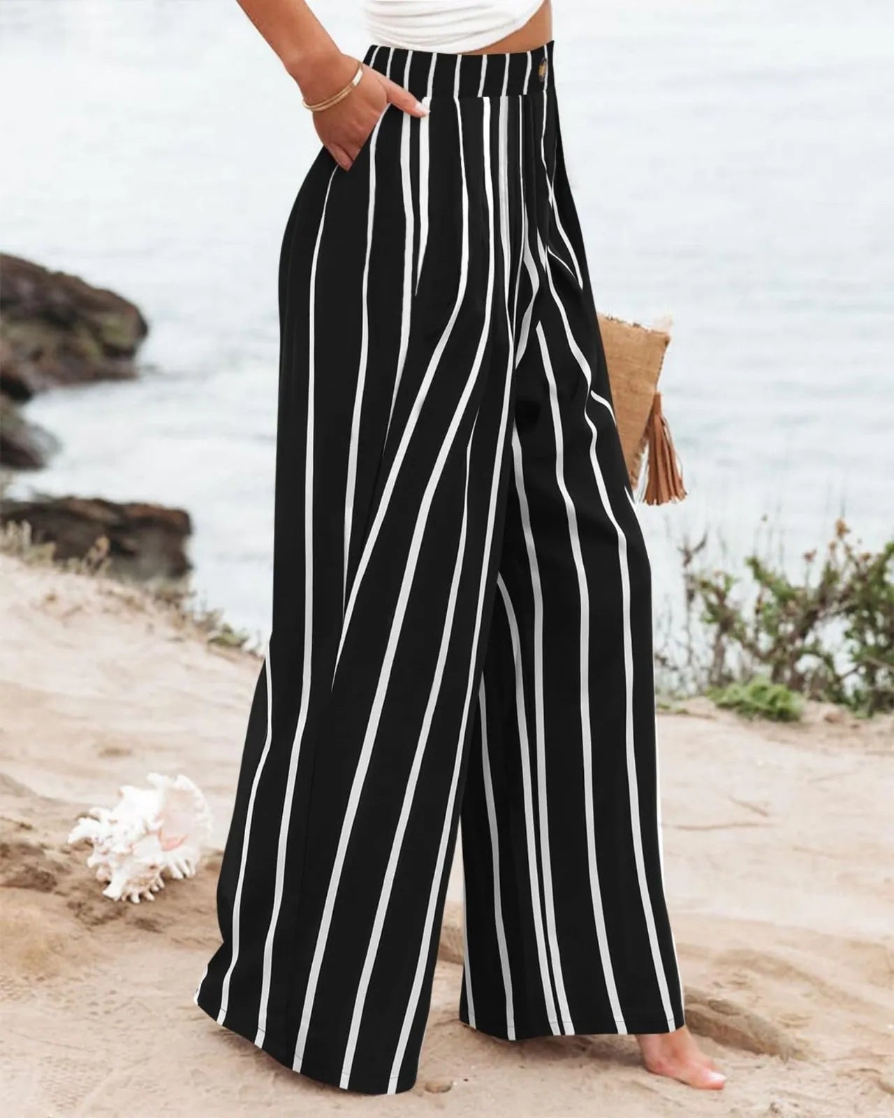 Black and white striped wide-leg pants worn by a person on a beach.