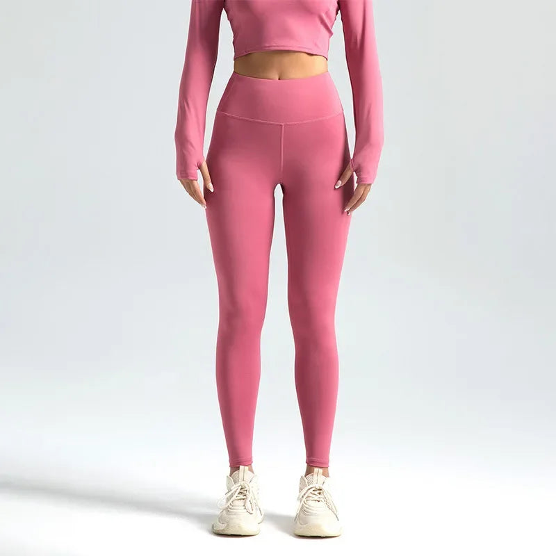 A woman wearing high-waist seamless booty-lifting yoga leggings in purple color, paired with a sports bra and white sneakers.