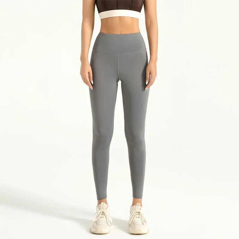 A woman wearing high-waist seamless booty-lifting yoga leggings in grey color, paired with a sports bra and white sneakers.