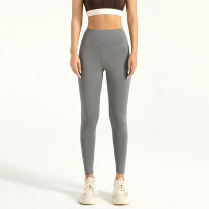A woman wearing high-waist seamless booty-lifting yoga leggings in grey color, paired with a sports bra and white sneakers.