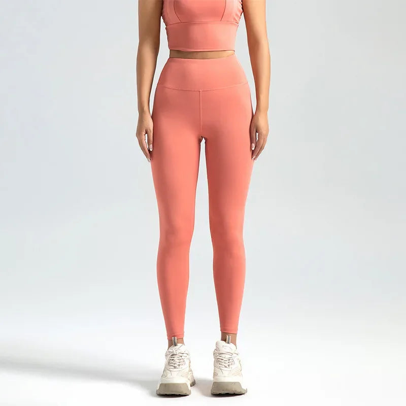 A woman wearing high-waist seamless booty-lifting yoga leggings in honey pomelo powder color, paired with a sports bra and white sneakers.