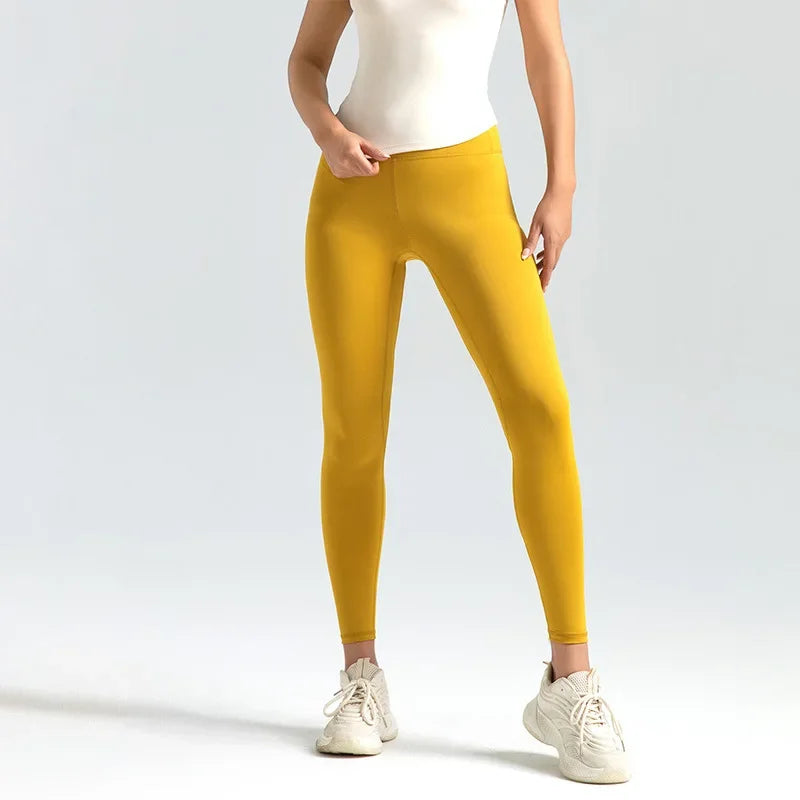 A woman wearing high-waist seamless booty-lifting yoga leggings in yellow color, paired with a sports bra and white sneakers.