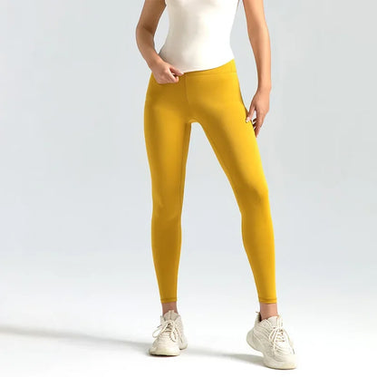 A woman wearing high-waist seamless booty-lifting yoga leggings in yellow color, paired with a sports bra and white sneakers.