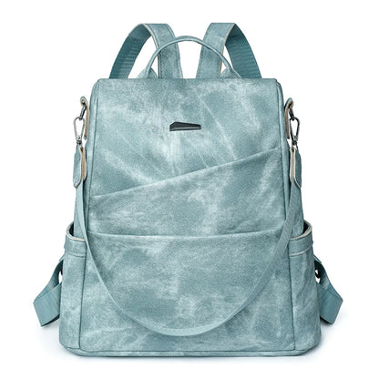 A green leather backpack for women with multiple compartments and an adjustable shoulder strap.