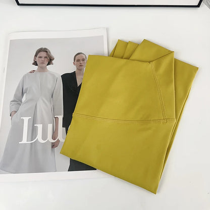 Mustard yellow fabric on a white surface with a magazine featuring two women in dresses.