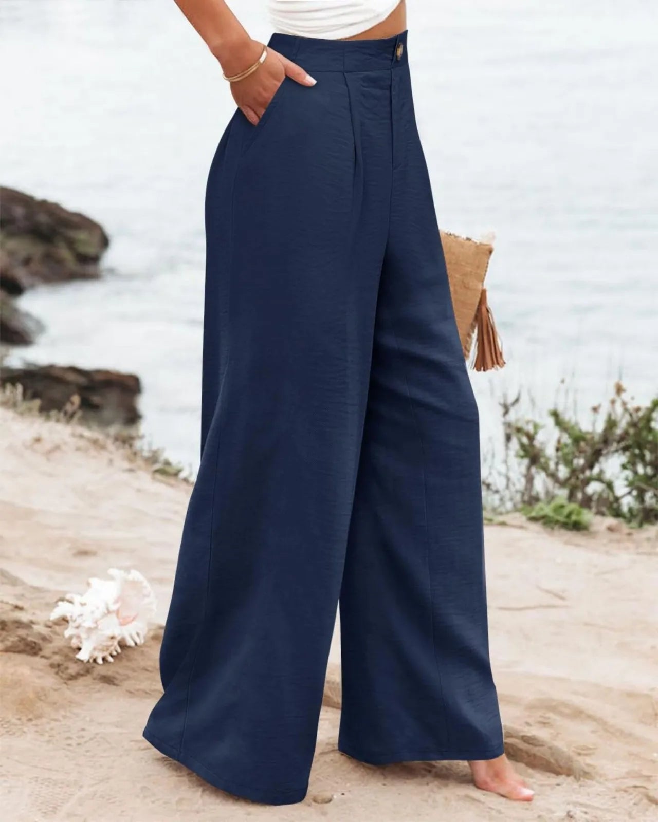 Navy wide-leg pants worn by a person on a beach.