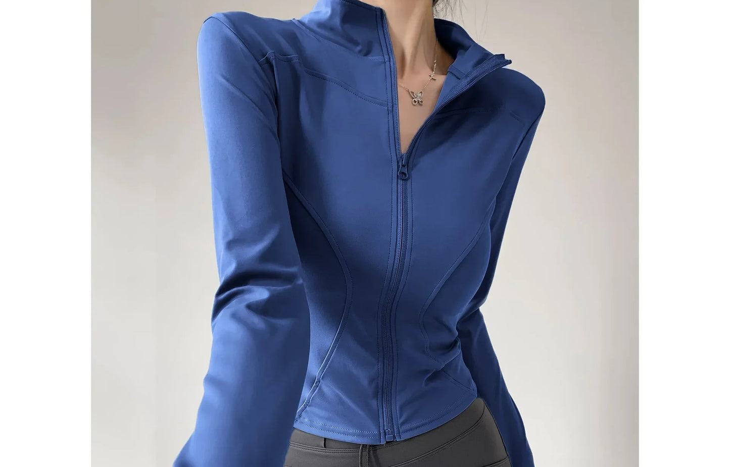 Person wearing a blue jacket and gray pants on a plain background