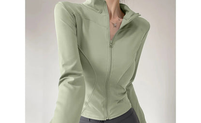 Person wearing a green jacket and gray leggings on a plain background