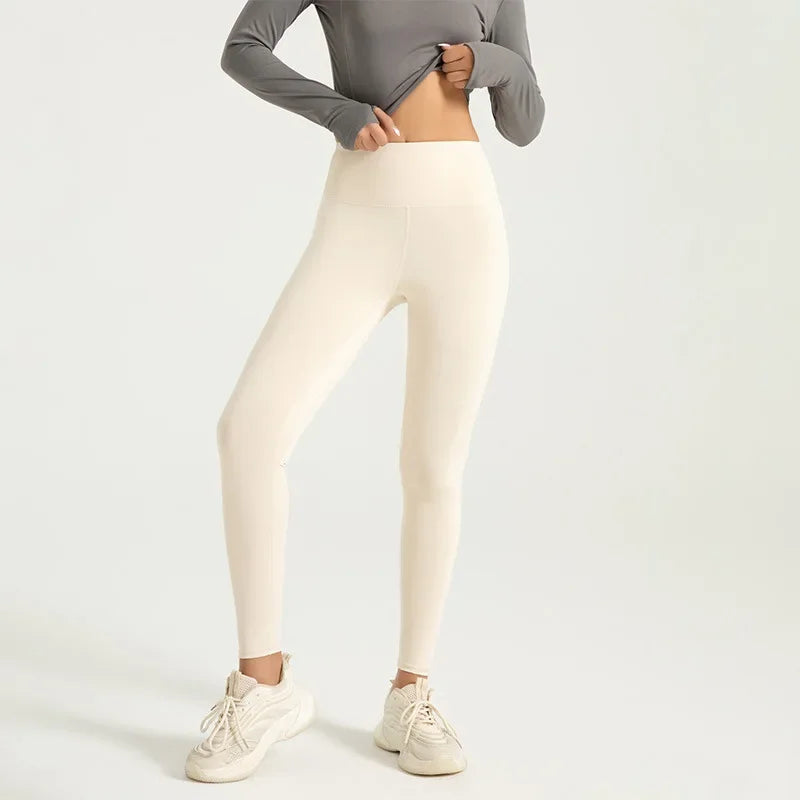 A woman wearing high-waist seamless booty-lifting yoga leggings in purple color, paired with a sports bra and white sneakers.