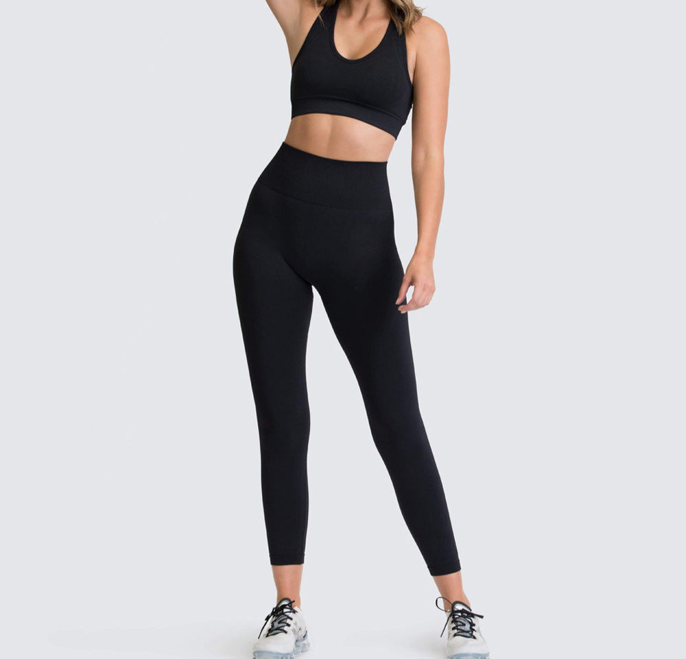 A woman wearing a matching set of green seamless fitness clothing, including high-waisted leggings and a sports bra, standing against a white background.