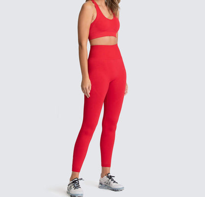A woman wearing a matching set of green seamless fitness clothing, including high-waisted leggings and a sports bra, standing against a white background.