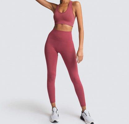 A woman wearing a matching set of green seamless fitness clothing, including high-waisted leggings and a sports bra, standing against a white background.