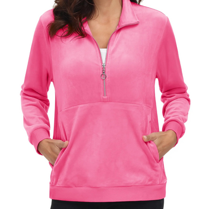 A woman wearing a rose red half zip fleece pullover hoodie with a hood, standing with hands in pockets.