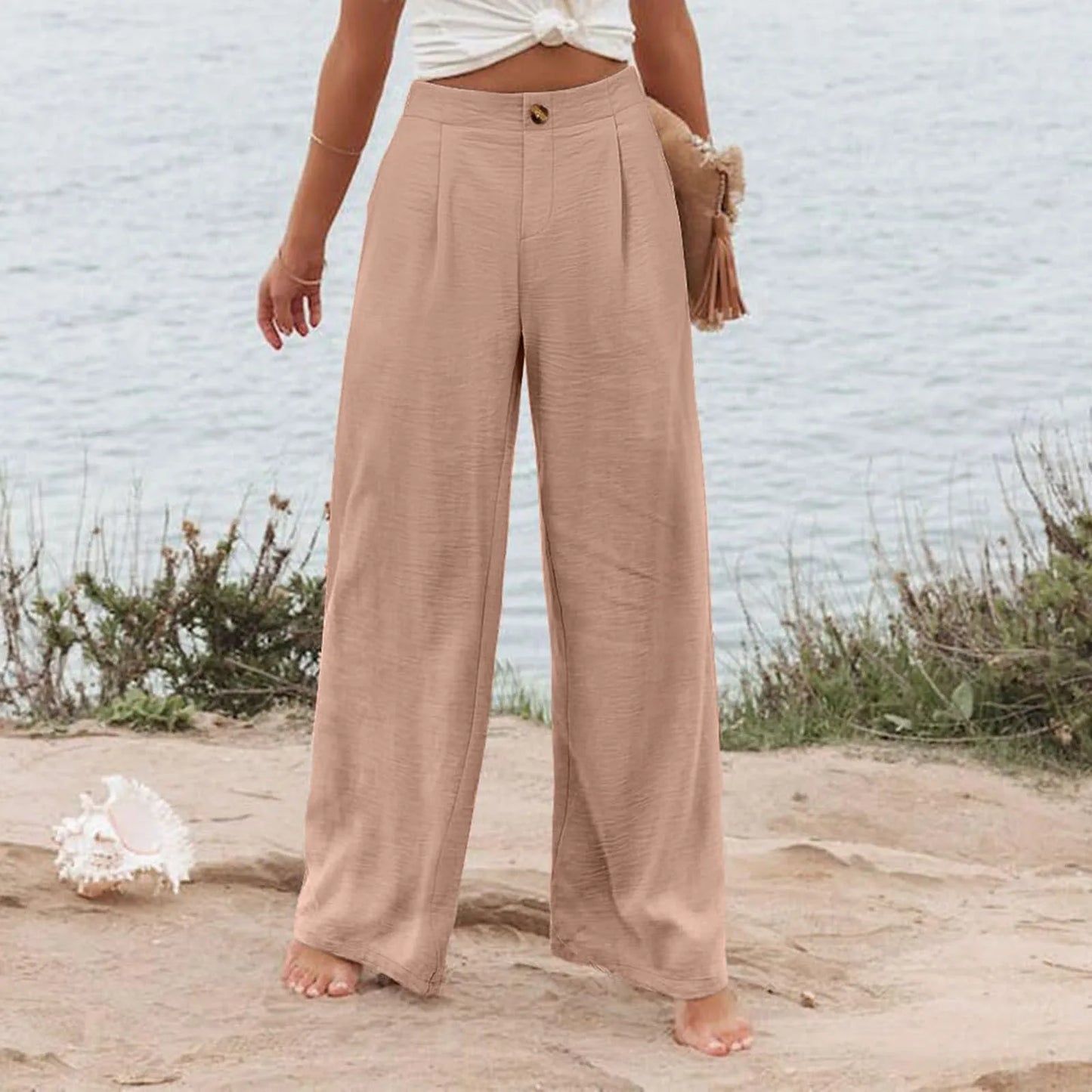 Person wearing beige wide-leg pants standing on a beach with a blurred background