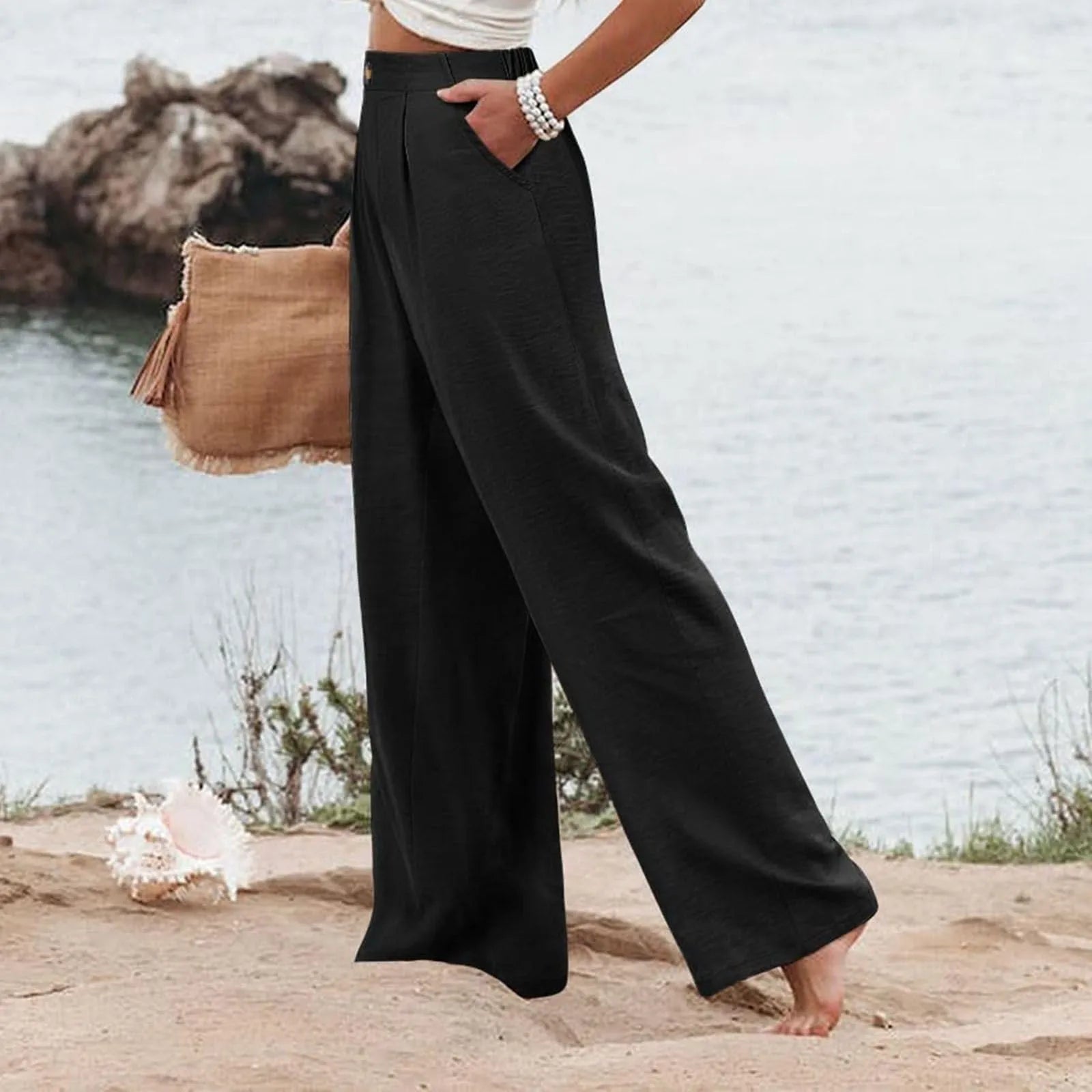 Person wearing black wide-leg pants by a body of water.