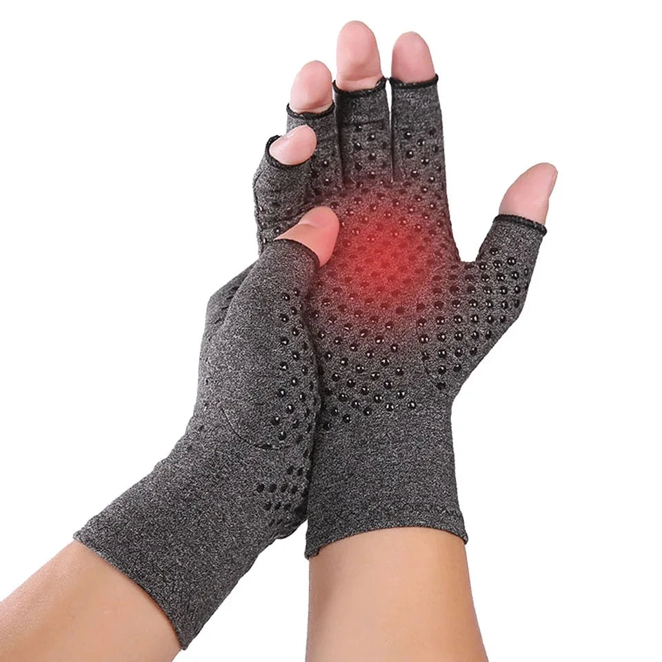 A pair of gray magnetic compression therapy gloves with an open-fingertip design, shown being worn by a person. The gloves appear to be made of a breathable fabric and are designed to provide joint support and pain relief.